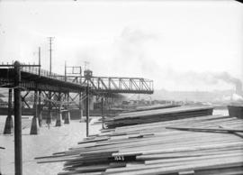 [Lumber piled near portion of Connaught Bridge (Cambie Street Bridge), damaged by fire]