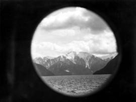 [View across Kwatna Inlet off Burke Channel through a porthole of S.S. "Cardena"]