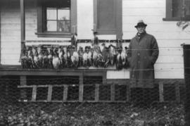 Eric W. Hamber standing beside ducks hanging in a row