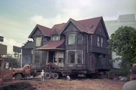 [Wide view of Hodson House raised on wheels during house relocation, 1 of 3]
