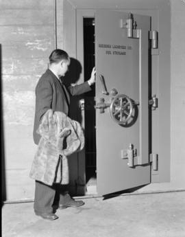 [Man with fur coat entering the fur storage vault at Nelsons Laundry]