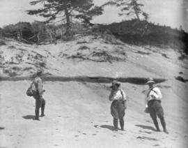 [Three unidentified people on a beach]