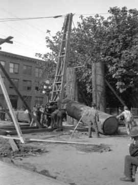 Men using crane to erect Lumberman's Arch on Pender Street near Hamilton Street, for visit of Duk...