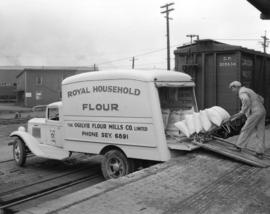 [Man loading Royal Household flour onto an] Ogilvie Flour Mill truck [at 1280 Homer Street]