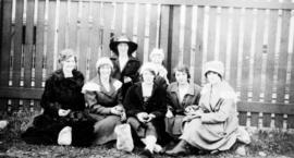 Pickets [women seated in front of picket fence in refinery yard]