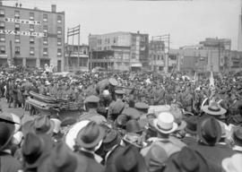 Large crowd gathered around automobile, men in military uniforms