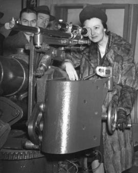 [A woman looks at a machine gun at the opening of Bessborough Armouries]