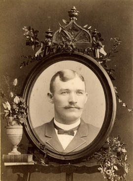 [Unidentified head and shoulders portrait of a man in an oval frame on a stand decorated with flo...