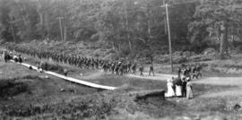 [Soldiers marching along a road with a work party of German prisoners of war]