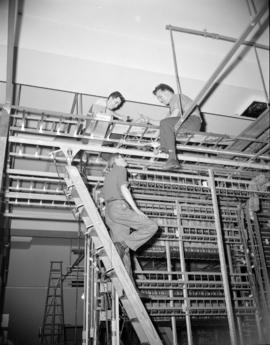 [B.C. Telephone technicians working on telephone line equipment as part of the changeover to a ne...