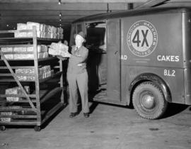 [Man loading loaves of bread into a 4X Canadian Bakeries Ltd. delivery truck]