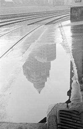[Train tracks and a reflection of the Marine Building in the water]