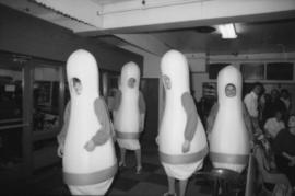Four people dressed in bowling pin costumes