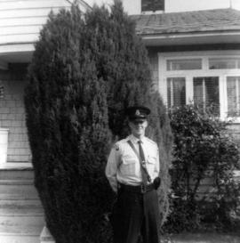 [Man in police uniform in front of house]