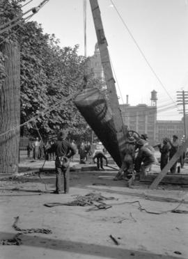 Men using crane and pulleys to erect Lumberman's Arch on Pender Street near Hamilton Street, for ...