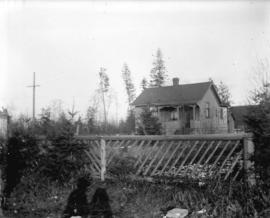 [View of house and yard behind fence]