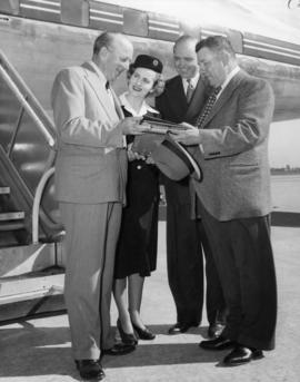 Mayor Thompson and three unidentified individuals standing by an airplane