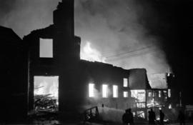 Silhouette of Denman Arena ablaze, with firefighters in foreground
