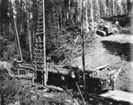 Upper Fraser Mills.  Loading logs on truck and small skidding tractor bringing in logs