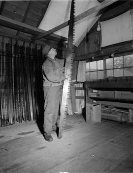 [Man inspecting saw blade at] Pacific Mills [on the] Queen Charlotte Islands