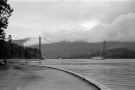 [View from the seawall of a ship passing under the Lions Gate Bridge under construction]