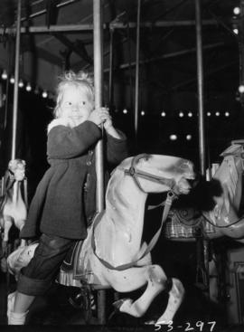 Young girl on merry-go-round in P.N.E. Gayway