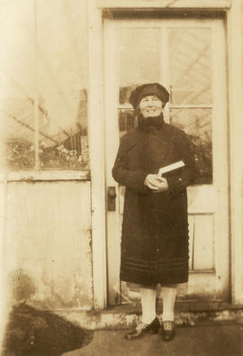 Miss Dodd in front of door to greenhouse