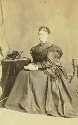 [Studio portrait of woman seated at a table]