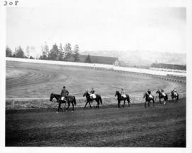 Horses and riders in post parade on racetrack