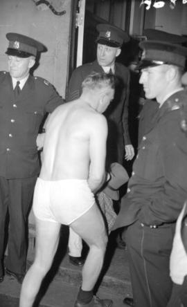 [Doukhobor man, dressed only in his underwear, entering the police station while policemen watch]