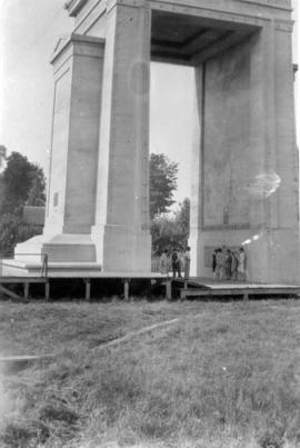 [Group of people standing under Peace Arch monument during its construction]