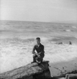 [Joseph Selsey seated on a rock in at the beach]