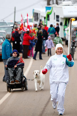 New Day 26 Torchbearer 54 Lucienne Donelle Easton runs the torch with son behind in Riverside-Alb...