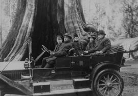 [Family in touring car parked at the Hollow Tree in Stanley Park]