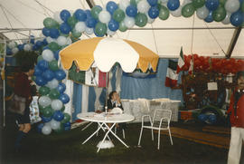 Woman sitting at patio table in Heritage Showcase tent