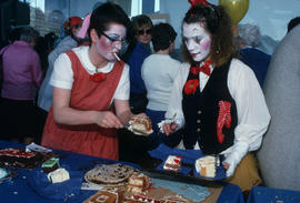 Women in face paint and costumes serving Vancouver's 99th birthday cake