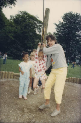 Woman helping children use playground flying fox