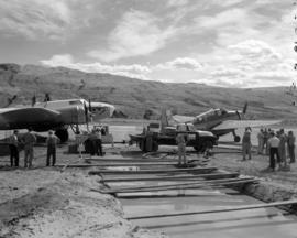 [Crew mixing water with fire control chemicals in a large pit for loading onto waiting water bomb...