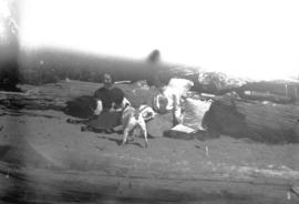 [Two women sitting against driftwood with dog at Greer's Beach (Kitsilano Beach)