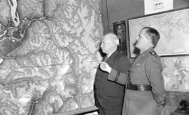 [Brigadier General Alex Ross and S.F.M. Moodie examining a large wall map]