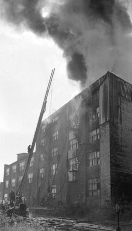 [Fireman on ladder truck at scene of a building fire]