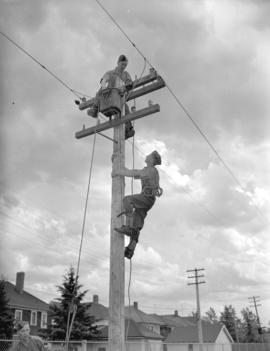 [Men climbing a utility pole near a] Calgary trade school