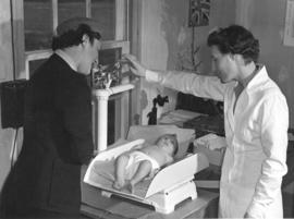 [Mrs. Nat Fenson watches as her baby Michael is weighed in a clinic in Burkeville]