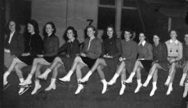[Women wtih skates sitting on the barrier at the side of the new ice rink]