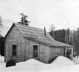 [Emil Peterson in front of his cabin]