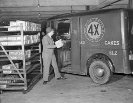 [Man loading bread into a 4X Canadian Bakeries Ltd. delivery van]