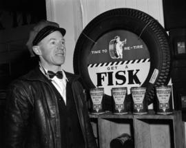 [B.A. Oil Company worker standing beside a Fisk tire and Peerless Motor Oil display]