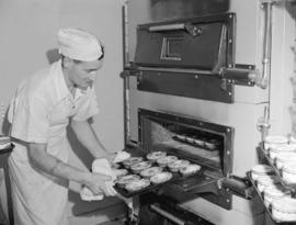 [Man taking pies out of oven at] Dale's [Roast Chicken] kitchen on Granville Street