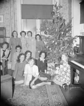[Group portrait of B.C. Telephone employees sitting by a Christmas tree]