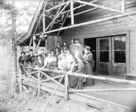 [Men and women assembled on porch of Capilano Canyon cottage built by George Grant McKay]